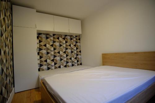 een kleine slaapkamer met een bed en een betegelde muur bij Villa Jean Julien - Le Capucin - Appartement T1 - 1 chambres - 4 personnes in Le Mont-Dore