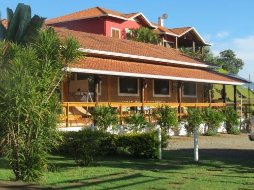 a house with a red roof and some palm trees at Pousada Sonho Meu in Itanhandu