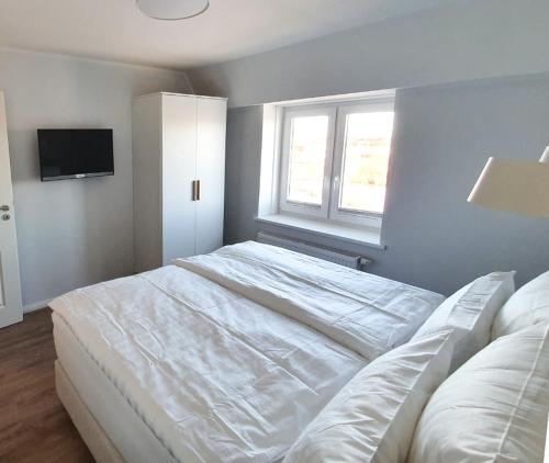 ein Schlafzimmer mit einem weißen Bett und einem Fenster in der Unterkunft Ferienwohnung Südwesthörn in Emmelsbüll-Horsbüll