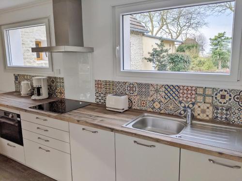 una cocina con fregadero y ventana en Maison Blanche en Côte de Nacre, en Mathieu
