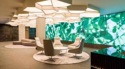 a lobby with chairs and a table and a large chandelier at Hotel Ilunion San Mamés in Bilbao