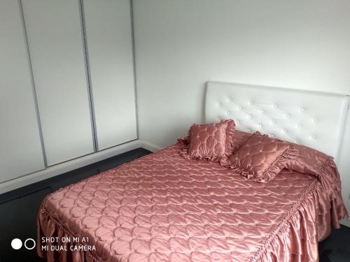 un letto con lenzuola rosa e due cuscini sopra di Vista Angular a Tandil