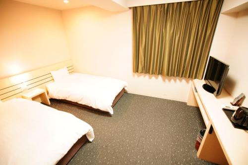 a hotel room with two beds and a television at Dormy Inn Akita in Akita