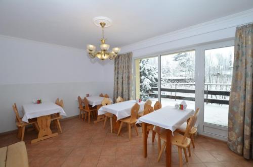 a dining room with white tables and chairs and a window at Villa Słonecznego Wzgórza in Zakopane