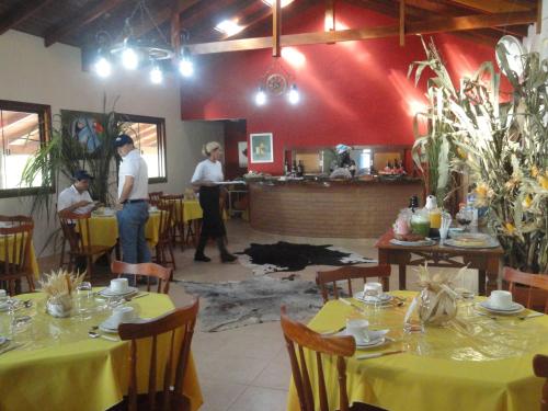 a group of people standing in a restaurant with tables at Pousada Sonho Meu in Itanhandu