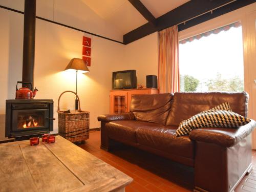 een woonkamer met een leren bank en een open haard bij Holiday Home in Gemmenich with Forest Views in Ten Eiken