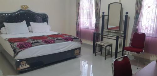 a bedroom with a bed and a red chair at DARRA HOMESTAY TORAJA in Rantepao