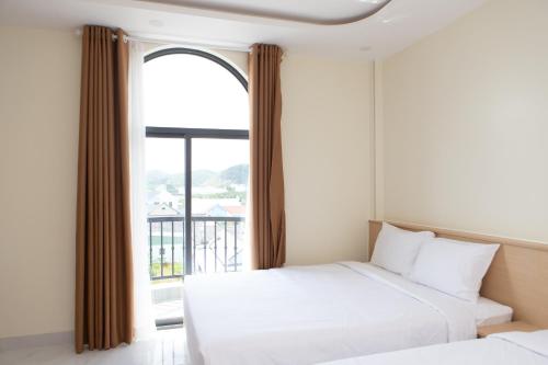 a bedroom with two beds and a large window at SUNRISE Hotel HA TIEN in Ha Tien