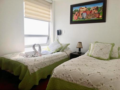 通哈的住宿－Hotel Parque Santander Tunja，一间卧室设有两张床,窗户墙上挂着一幅画。
