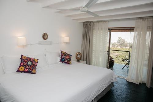 a bedroom with a large white bed and a window at Empedrada Ranch & Lodge - Hotel Asociado Casa Andina in Caral