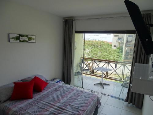 1 dormitorio con 1 cama con almohadas rojas y balcón en Flat Condomínio Fazenda Monte Castelo - Gravatá PE, en Recife