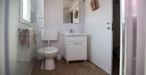 uma casa de banho branca com um WC e um lavatório em Mobile home Frangipani 2 em Biograd na Moru