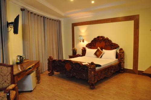 a bedroom with a large bed with a wooden headboard at Angkor Comfort Hotel in Battambang
