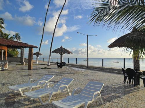 a group of chairs and umbrellas on a beach at Flats Privé Village Galés in Maragogi