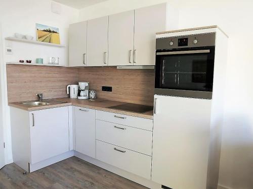 uma cozinha com armários brancos e um micro-ondas preto em Vier Jahreszeiten 2-53 em Grossenbrode