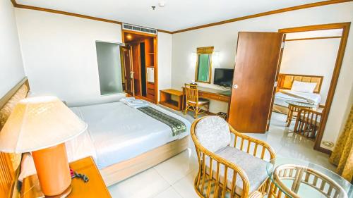 a hotel room with a bed and a desk and a chair at K Park Grand Hotel in Surat Thani