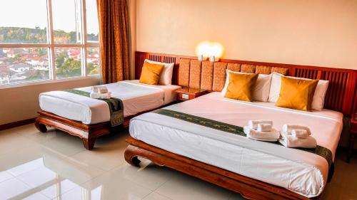 a hotel room with two beds and a window at K Park Grand Hotel in Surat Thani