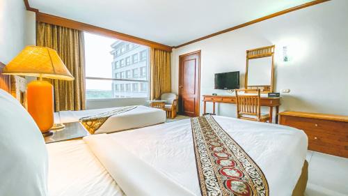 a hotel room with two beds and a desk at K Park Grand Hotel in Surat Thani