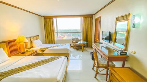 a hotel room with two beds and a desk at K Park Grand Hotel in Surat Thani