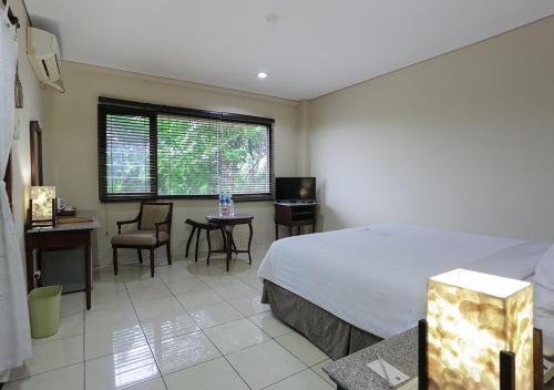 a bedroom with a bed and a table and chairs at The Jayakarta Suites Komodo Flores in Labuan Bajo