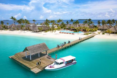 a boat on the water next to a tropical island at Sun Siyam Iru Veli - 24 Hours Premium All-Inclusive with Free Transfers in Dhaalu Atoll