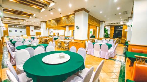 a banquet hall with green tables and white chairs at K Park Grand Hotel in Surat Thani