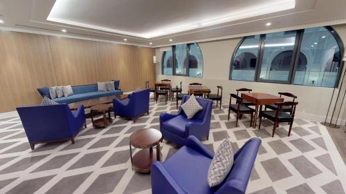 a waiting room with blue chairs and tables and windows at The Hotel Galleria Jeddah, Curio Collection by Hilton in Jeddah