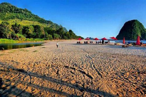 a beach with umbrellas and a person walking on the sand at The Wisma Pulau Merah in Pasanggaran