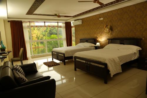 a bedroom with two beds and a couch and a window at Riverside Inn Homestay in Cochin
