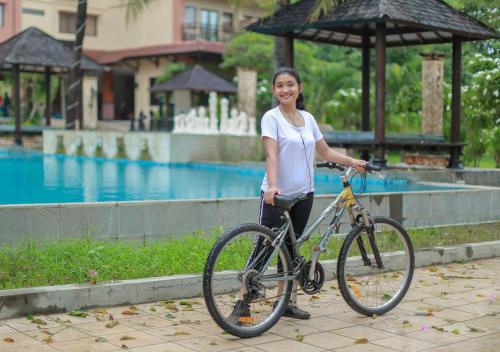 a woman holding a bike in front of a pool at The Jayakarta Suites Komodo Flores in Labuan Bajo