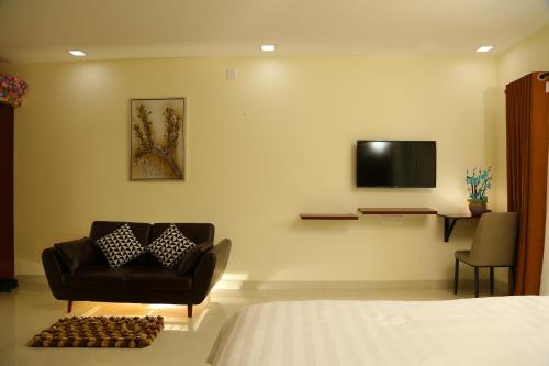 a bedroom with a couch and a tv on the wall at Riverside Inn Homestay in Cochin
