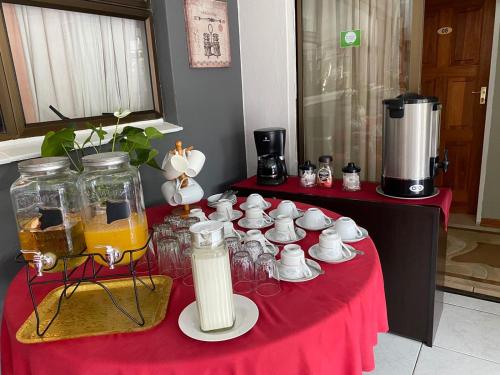 a table with a red table cloth with cups and tea sets at Marion Lodge in Johannesburg