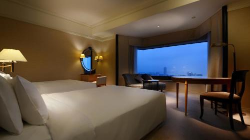 a hotel room with a bed and a desk and a window at Hotel New Otani Makuhari in Chiba