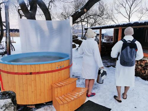 two women standing next to a hot tub in the snow at Holiday House Niedras Jurmala in Jūrmala