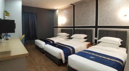 a hotel room with three beds and a desk at GOOD 9 HOTEL - Cahaya Kota Puteri in Pasir Gudang