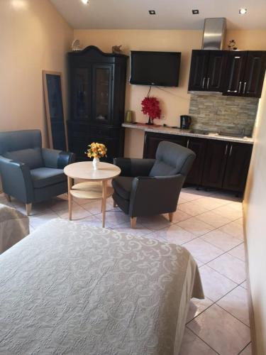 a living room with couches and a table and a kitchen at Aroma Skuodiškio Užeiga in Skuodas