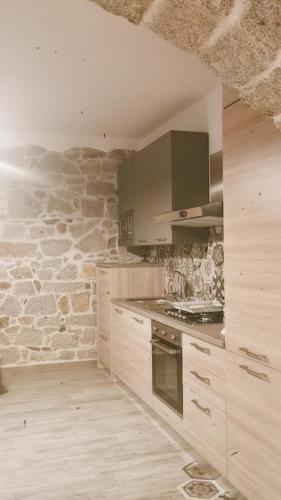 a kitchen with wooden cabinets and a stone wall at viche viche in Orgosolo