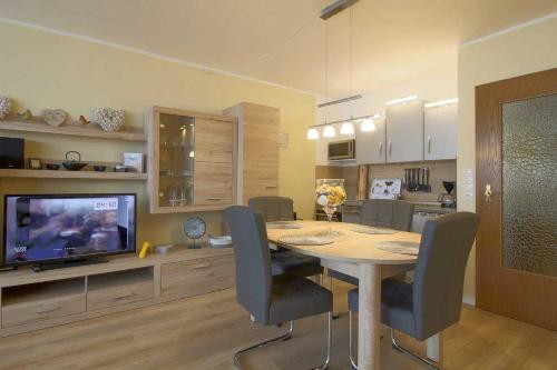 une salle à manger avec une table, des chaises et une télévision dans l'établissement Apartment 239, à Hohegeiss