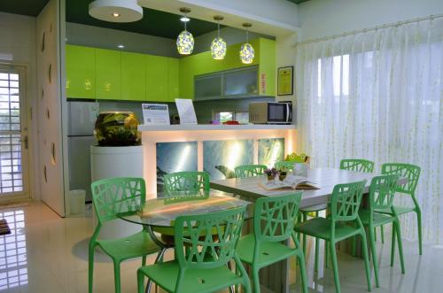 a dining room with a table and green chairs at Fish Nest Villa 宜蘭親子包棟民宿 戲水池 歡唱 代訂晚餐 in Dongshan