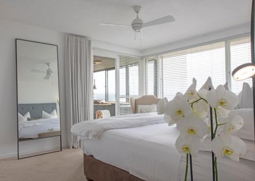 um quarto branco com uma cama com flores brancas em Best View @ No 2 em Plettenberg Bay