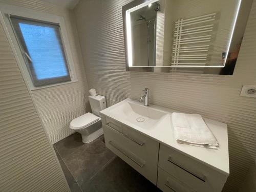 Un baño con lavabo, inodoro y espejo. en Petite Maison Andernos, en Andernos-les-Bains