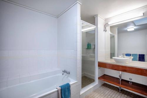 a white bathroom with a tub and a sink at Heart of Airlie Beach Apartment in Airlie Beach