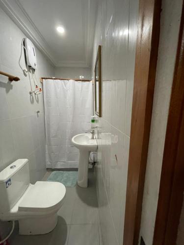 a white bathroom with a toilet and a sink at Theo Good Life Hotel in Big Ada