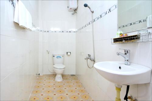a white bathroom with a toilet and a sink at Blue Clouds Homestay in Hoi An