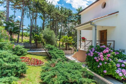 a garden outside a house with flowers and trees at Apartments Pino Rabac in Rabac