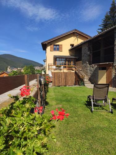 a house with a yard with a chair and flowers at Cal Masuret in Planoles