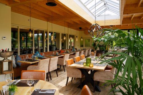 un restaurante con mesas de madera, sillas y plantas en Hotel Jachtlust, en Borne