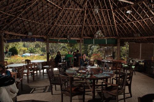 a restaurant with tables and chairs and people sitting around them at Elephant Valley Eco Farm Hotel in Kodaikānāl