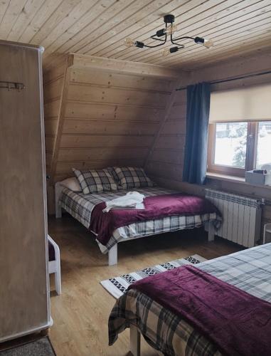 a bedroom with two beds in a log cabin at Pokoje u Małgorzatki in Murzasichle