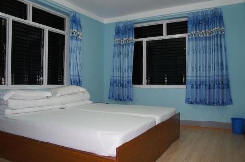 a bed in a room with blue walls and windows at Hotel Mount Paradise in Nagarkot